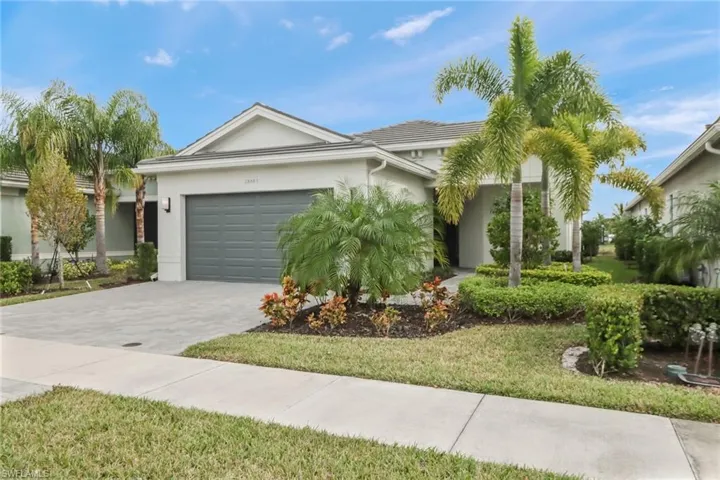 Ranch-style home with stucco siding, an attached garage, decorative driveway, and a front yard