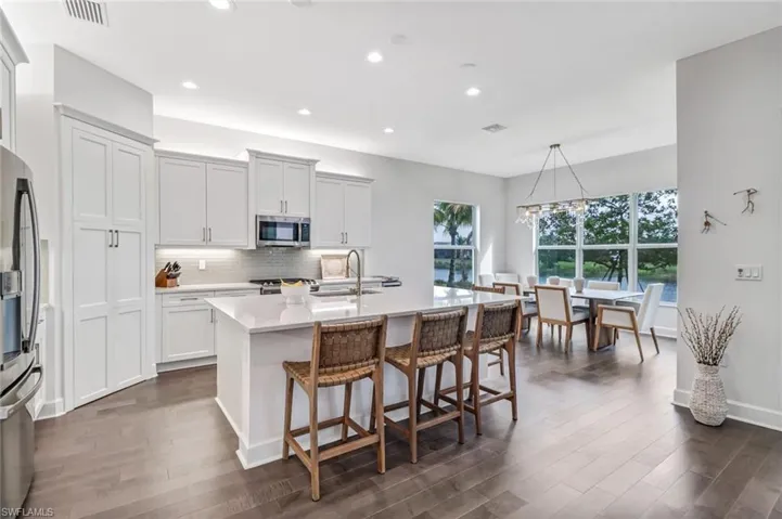 Kitchen featuring tasteful backsplash, a kitchen bar, an island with sink, appliances with stainless steel finishes, and light stone counters
