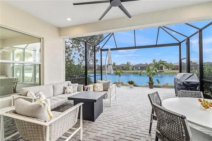 View of patio with a sunroom, a water view, glass enclosure, a residential view, and area for grilling