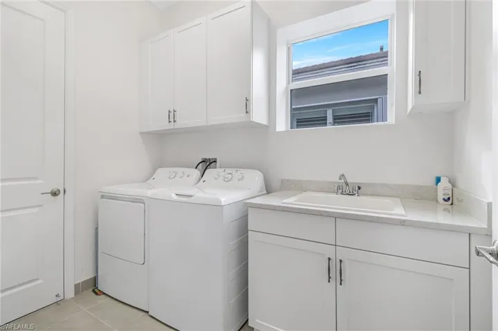 Laundry room featuring cabinet space, light tile patterned floors, and washing machine and dryer