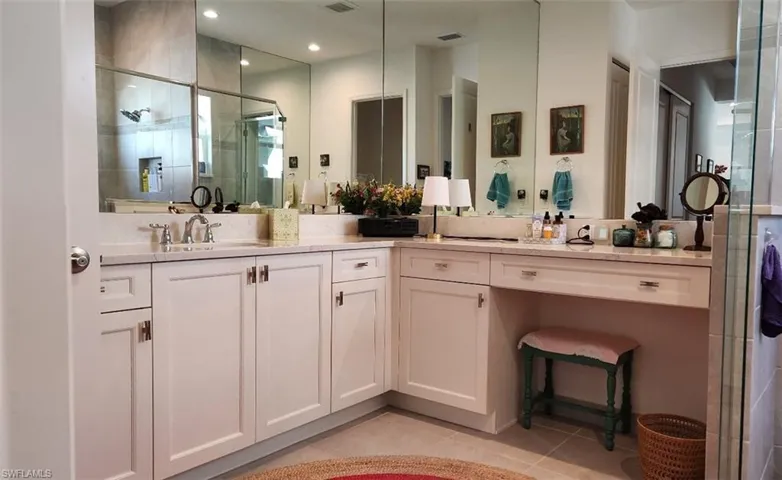 Full bathroom featuring light tile patterned flooring, double vanity, and a stall shower