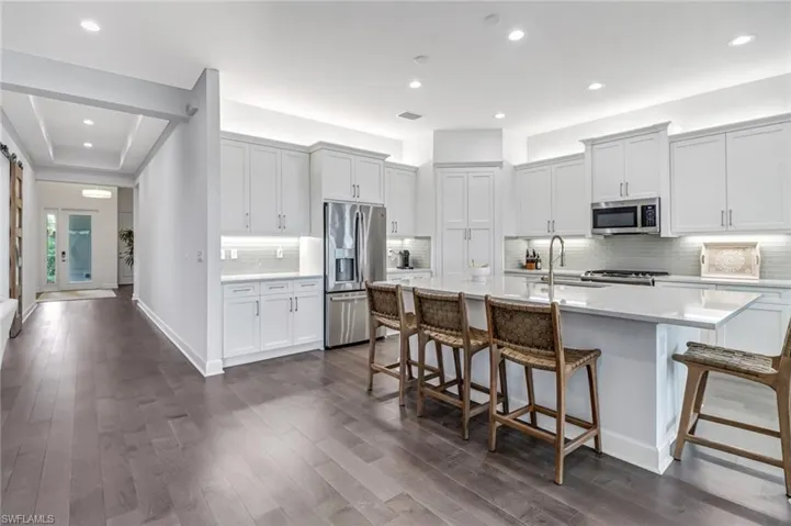 Kitchen featuring a kitchen breakfast bar, tasteful backsplash, appliances with stainless steel finishes, a center island with sink, and recessed lighting