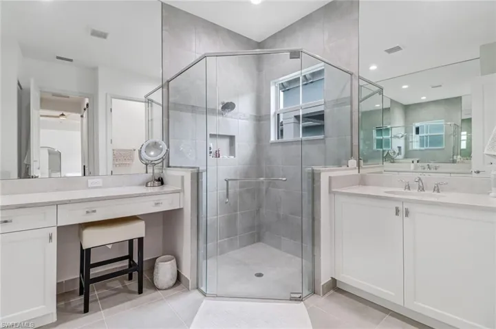 Bathroom with a stall shower, light tile patterned floors, vanity, and recessed lighting