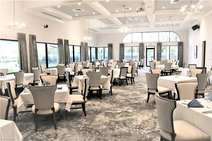 Carpeted dining space with a chandelier, beamed ceiling, coffered ceiling, and a towering ceiling