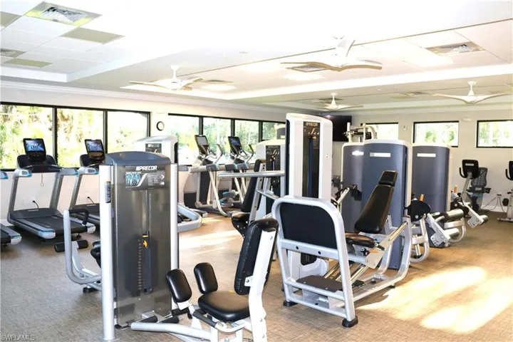 Gym with a ceiling fan, a tray ceiling, and visible vents