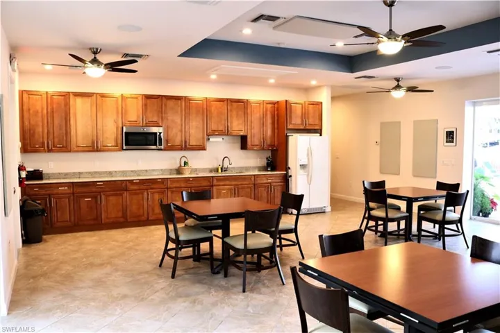 Kitchen featuring visible vents, white fridge with ice dispenser, stainless steel microwave, and a sink