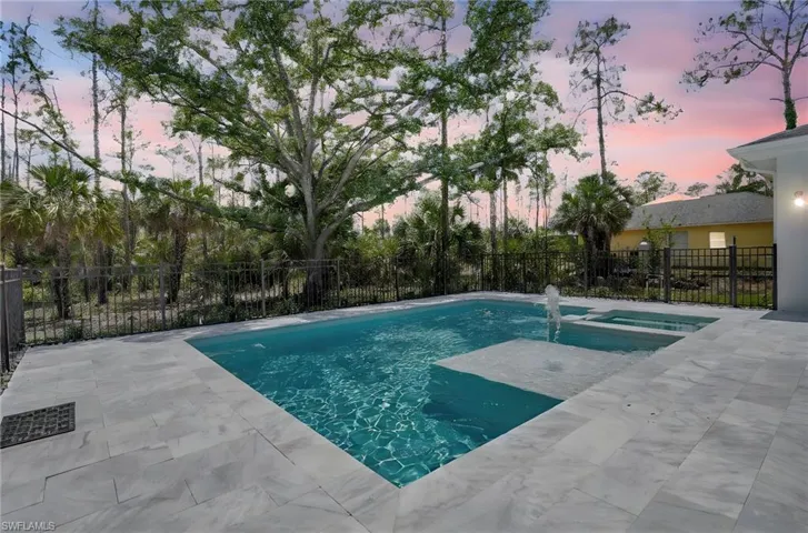 View of swimming pool with a patio, fence, and a pool with connected hot tub