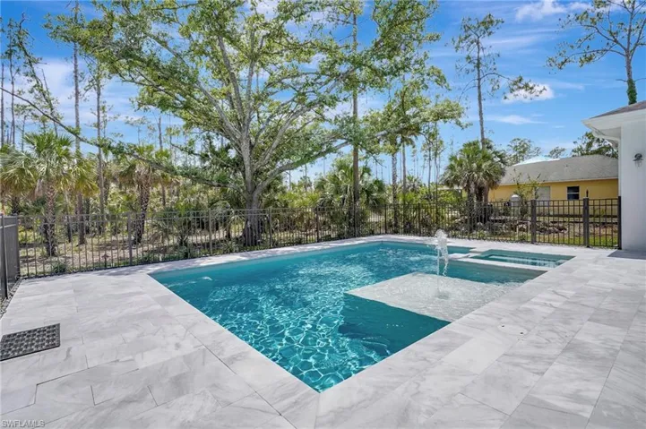 View of swimming pool with fence, a pool with connected hot tub, and a patio