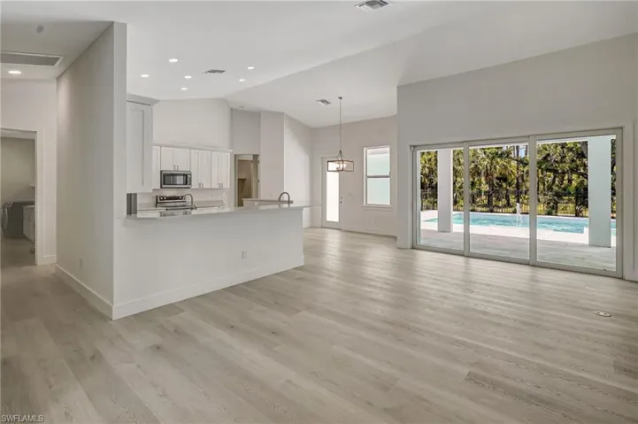 Unfurnished living room featuring high vaulted ceiling, baseboards, light wood-style flooring, and recessed lighting
