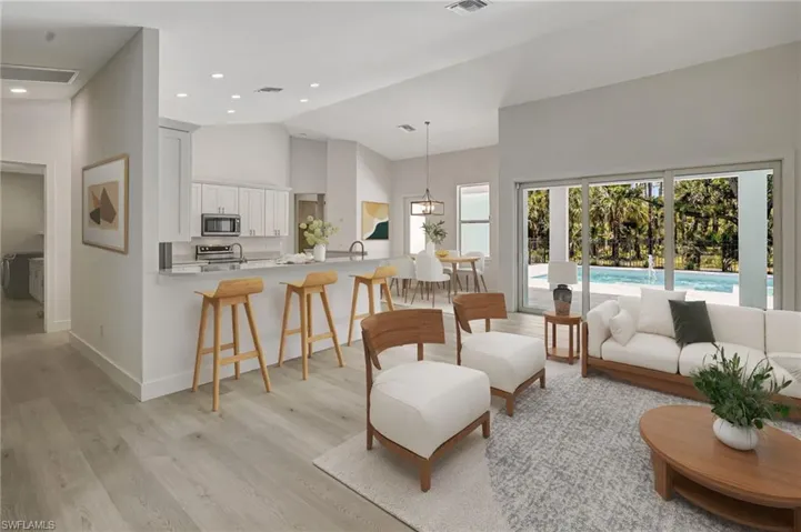 Living area featuring light wood-style floors, baseboards, high vaulted ceiling, and recessed lighting
