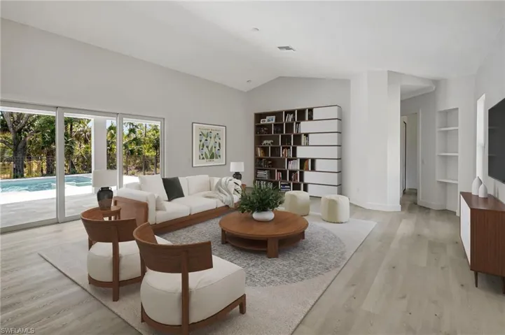 Living area with light wood-style floors, lofted ceiling, built in features, and baseboards
