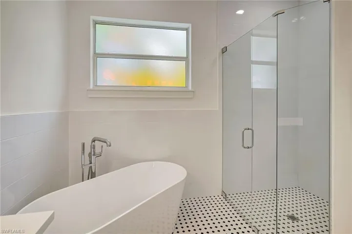 Full bath featuring tile walls, a shower stall, and a freestanding tub