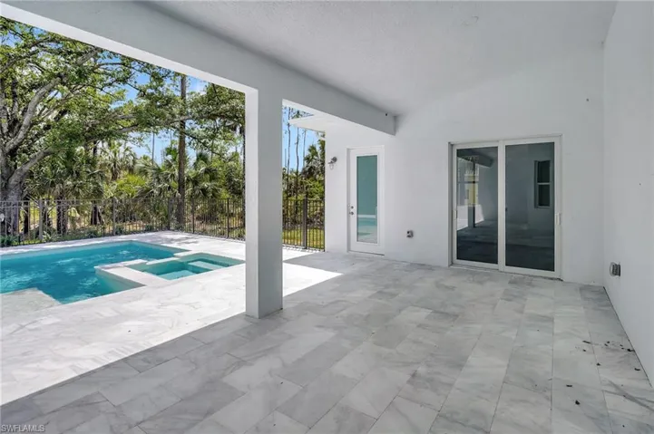 View of swimming pool featuring a patio, fence, and a pool with connected hot tub