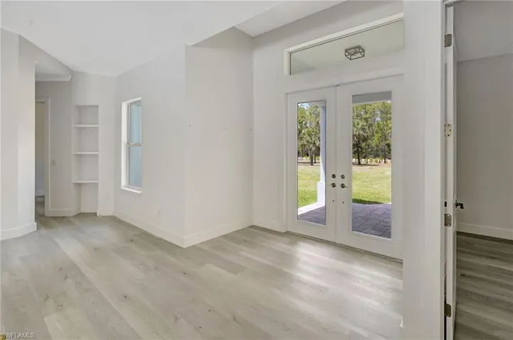 Doorway with french doors, light wood-style floors, baseboards, and built in shelves