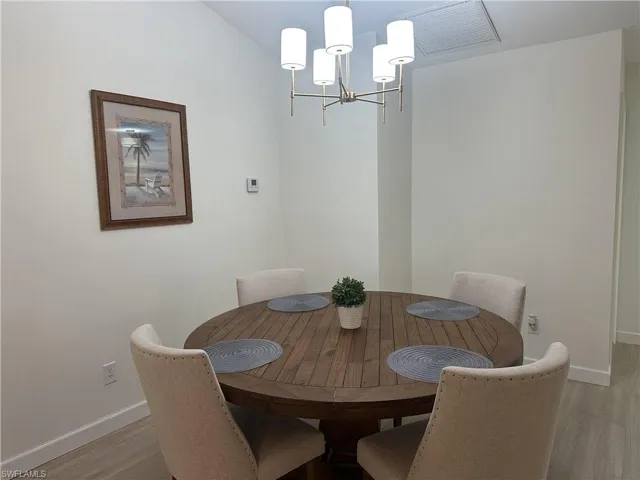 Dining space with light wood finished floors and a chandelier