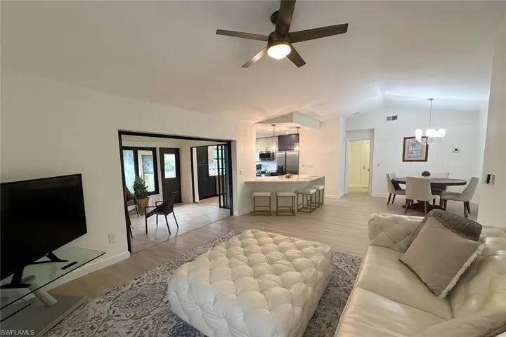 Living area with light wood-style flooring, lofted ceiling, ceiling fan, and a chandelier