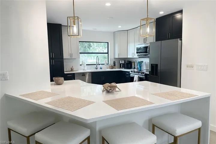 Kitchen with a breakfast bar, tasteful backsplash, appliances with stainless steel finishes, a peninsula, and dark cabinets