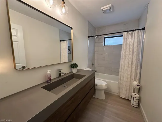 Full bath featuring shower / bathtub combination with curtain, light wood-style floors, and vanity
