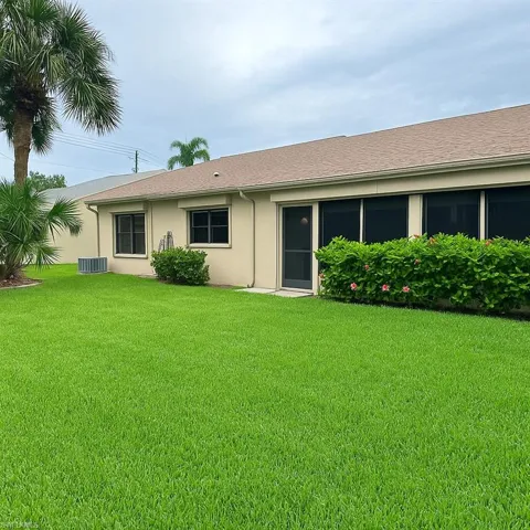 Rear view of property with a yard, stucco siding, and a shingled roof