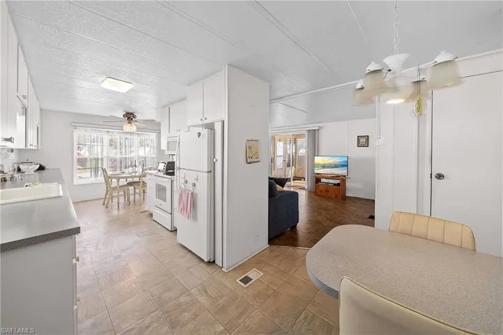 Kitchen featuring white cabinetry, white appliances, healthy amount of natural light, a ceiling fan, and a textured ceiling