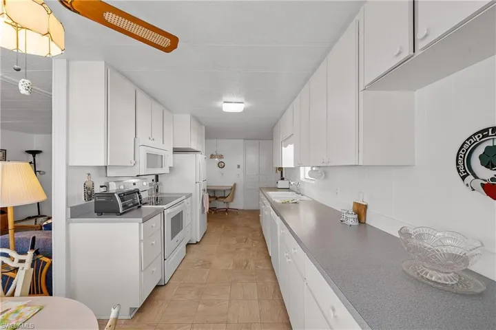 Kitchen featuring white cabinetry, white appliances, and dark countertops