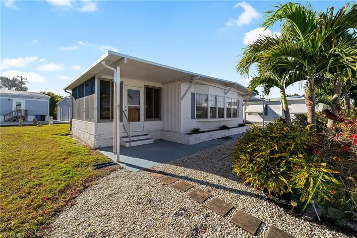 View of side of property with entry steps, a yard, a sunroom, and a patio