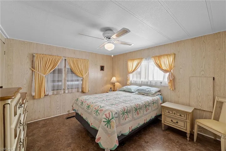 Bedroom featuring wood walls, a ceiling fan, and a textured ceiling