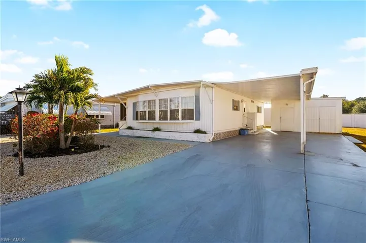 Manufactured / mobile home featuring an attached carport, driveway, and a patio