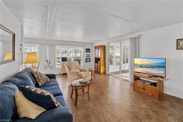 Living room with a textured ceiling, wood walls, and tile patterned floors