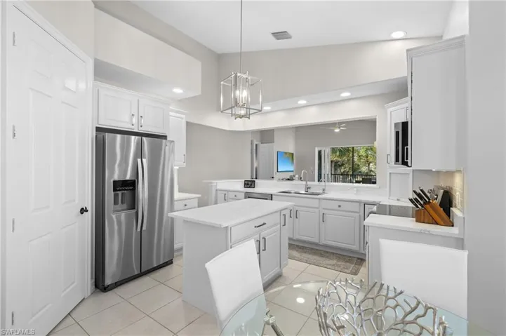 Kitchen with stainless steel fridge with ice dispenser, light tile patterned floors, light countertops, a sink, and hanging light fixtures