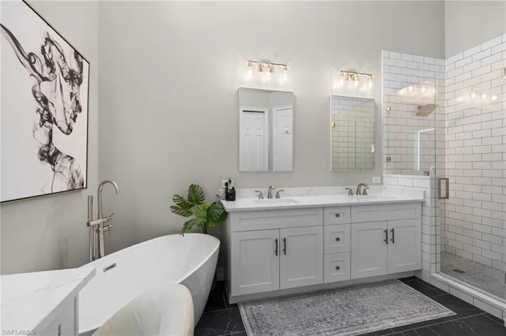 Full bath featuring a sink, a shower stall, a freestanding tub, and double vanity