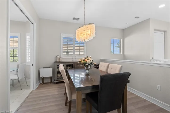 Dining space with visible vents, light wood-type flooring, plenty of natural light, and a notable chandelier