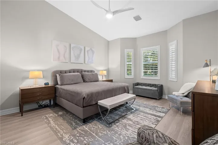 Bedroom featuring visible vents, baseboards, ceiling fan, light wood finished floors, and vaulted ceiling