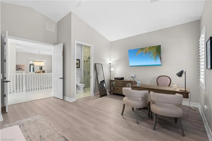 Office with high vaulted ceiling, an inviting chandelier, visible vents, light wood finished floors, and baseboards
