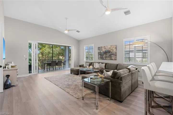Living room with visible vents, light wood-style flooring, a ceiling fan, and vaulted ceiling