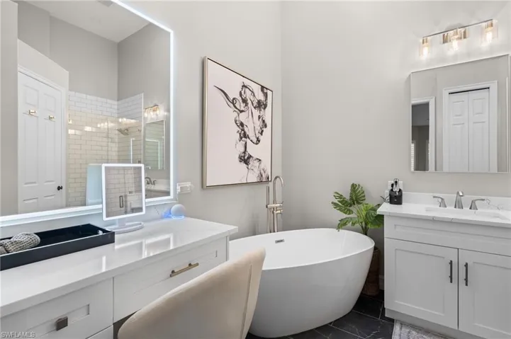 Bathroom featuring a sink, two vanities, marble finish floor, and a freestanding tub