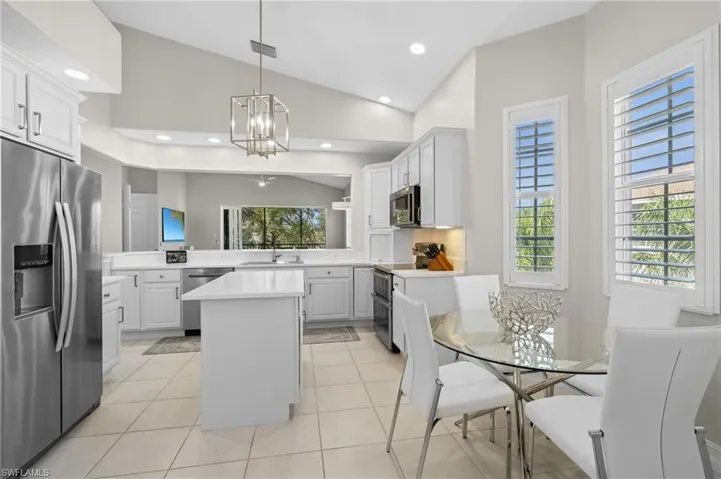Kitchen featuring appliances with stainless steel finishes, a center island, light countertops, lofted ceiling, and a sink