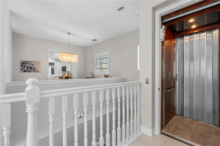 Corridor with tile patterned flooring, an upstairs landing, visible vents, and an inviting chandelier