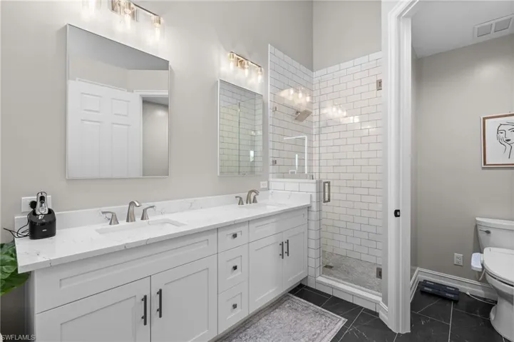 Full bathroom featuring visible vents, a stall shower, a sink, and toilet