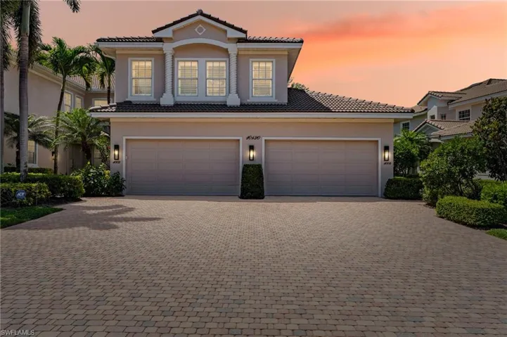 View of front facade with driveway, stucco siding, and a tiled roof