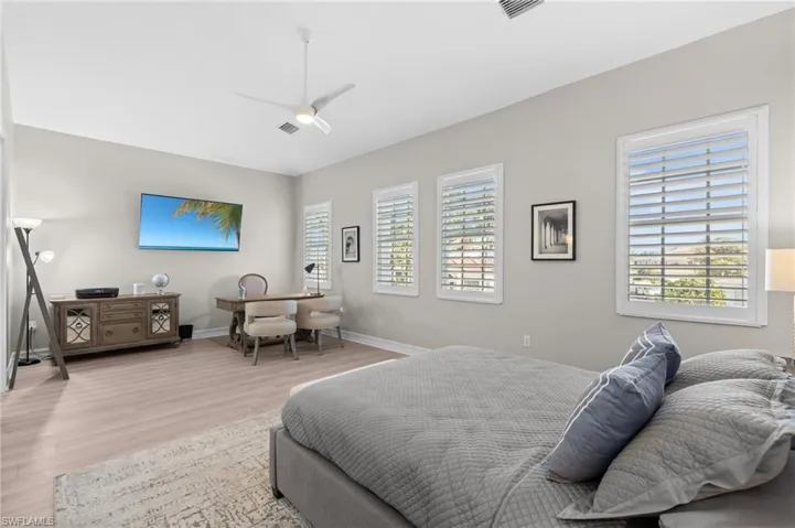 Bedroom featuring baseboards, a ceiling fan, visible vents, light wood-style floors, and lofted ceiling