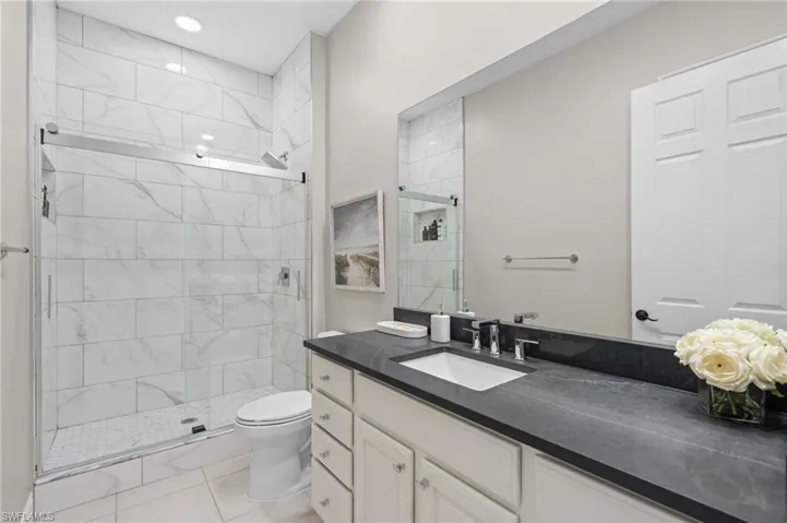 Full bath featuring toilet, a stall shower, vanity, and recessed lighting