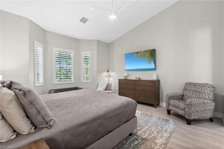 Bedroom featuring visible vents, baseboards, light wood finished floors, and lofted ceiling
