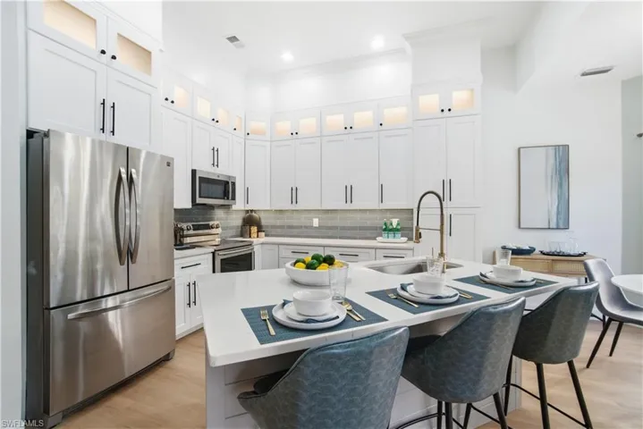 A beautifully redesigned kitchen with quartz counters, illuminated display white shaker cabinetry, and a welcoming breakfast bar perfect for casual dining.