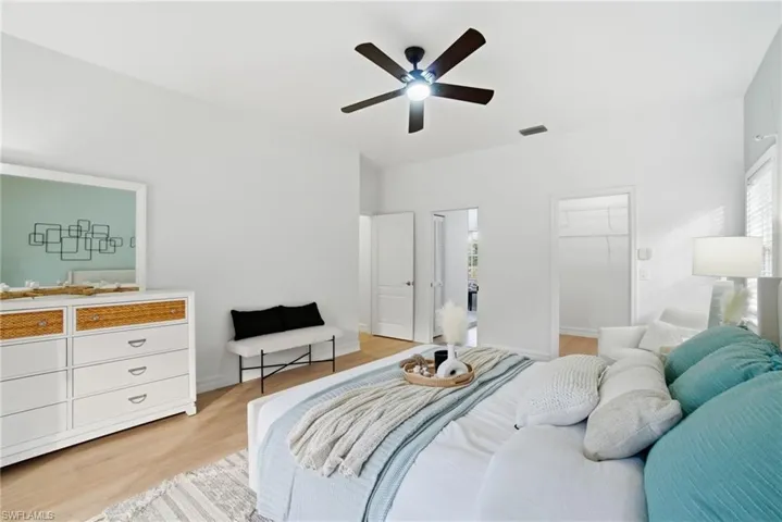 a light filled primary bedroom offers new LVP flooring, spacious walk-in closet and access to the deck and pool