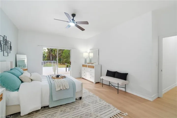 A tranquil primary bedroom offers new LVP flooring and serene views of the property's lush, private 2.5 acres