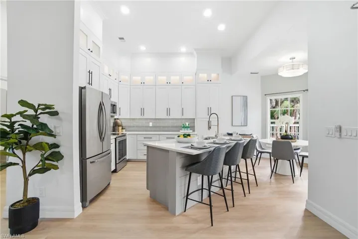 Quartz countertops, softly lit glass display cabinets, and a stylish breakfast bar make this kitchen as functional as it is beautiful.