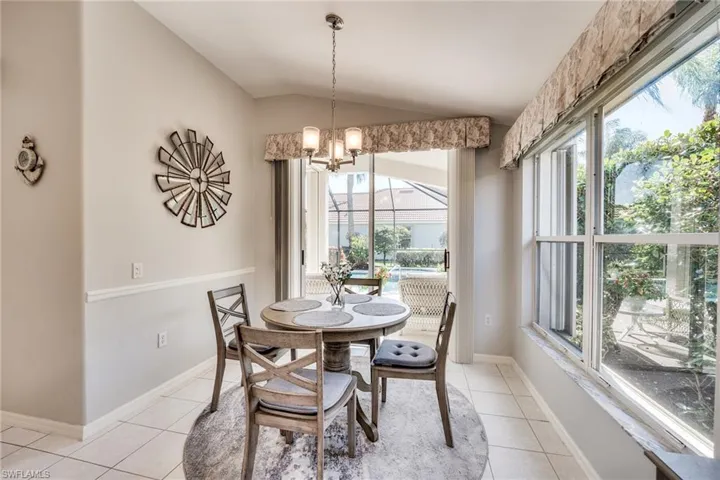 Tiled dining space featuring vaulted ceiling and a chandelier