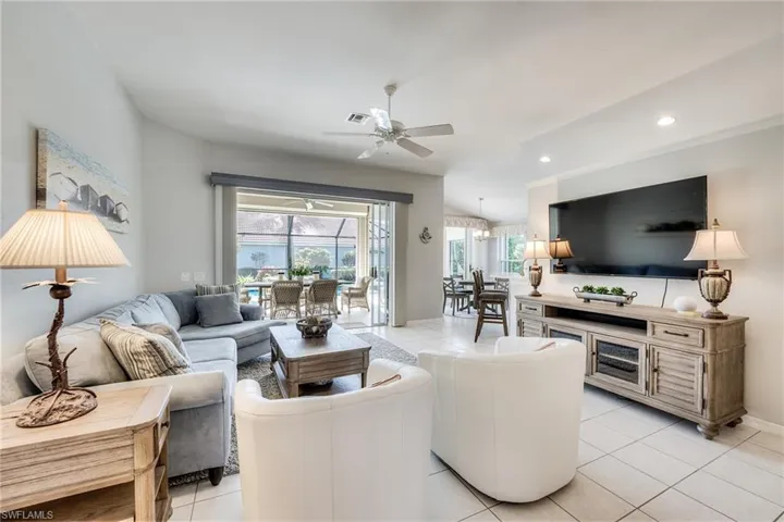 Living room with light tile patterned floors, vaulted ceiling, and ceiling fan