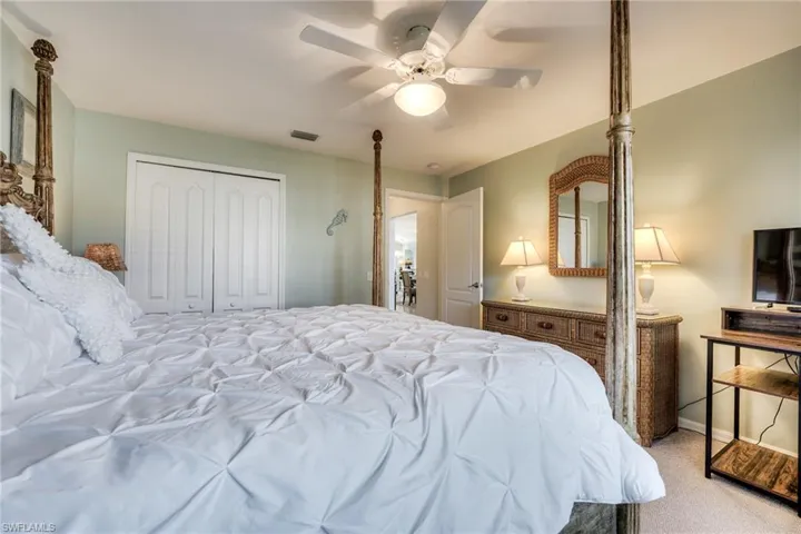 Bedroom with light colored carpet, a closet, and ceiling fan